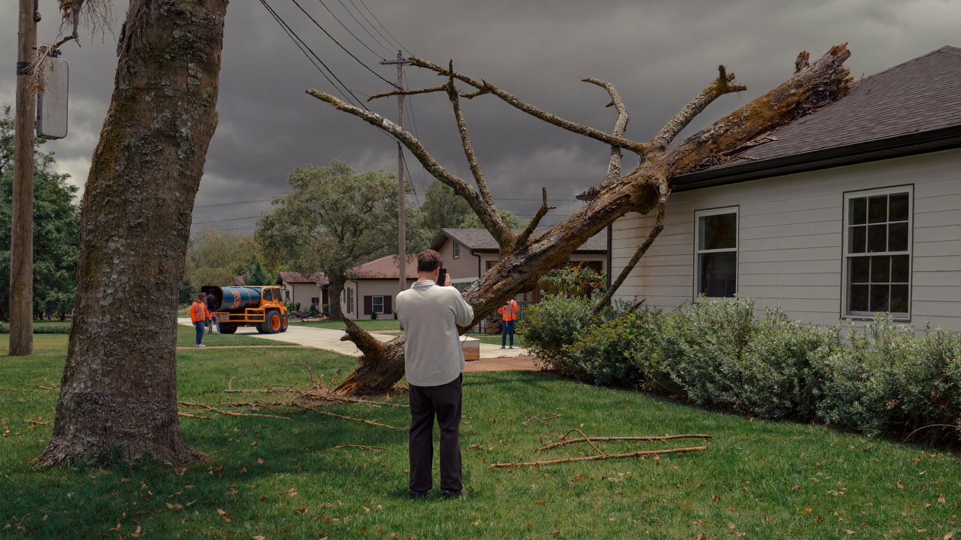 Homeowner photographing a storm-fallen limb on a Jacksonville roof for an insurance claim